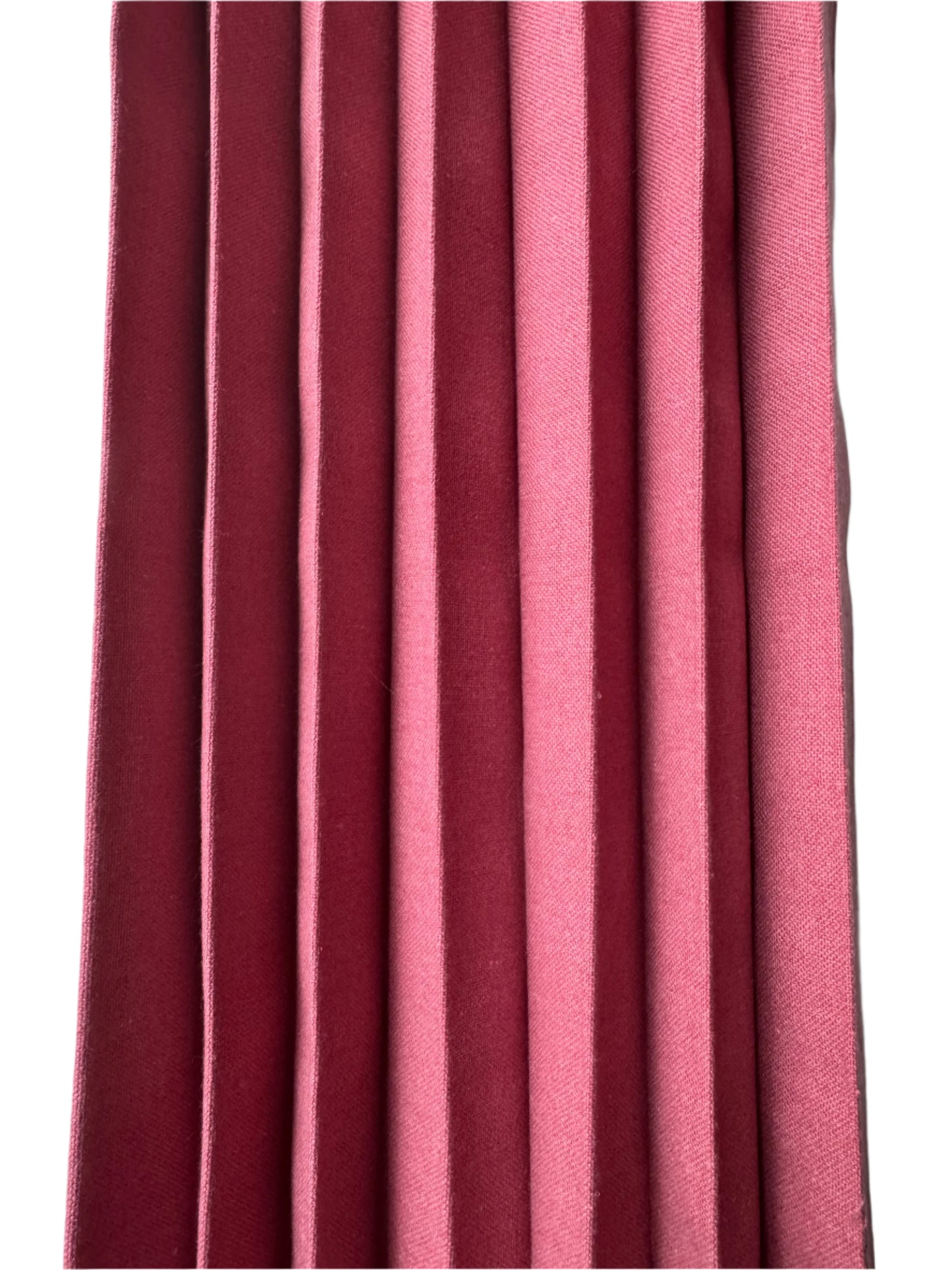 A close-up of folded cotton napkins in shades of burgundy and soft pink, showcasing crisp, evenly spaced pleats with neat stitching along the edges