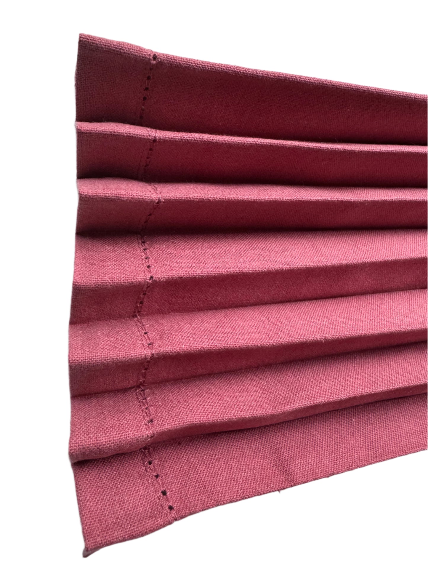 Close-up of burgundy cotton napkins neatly pleated, showcasing the fine stitching and clean edges for an elegant, well-crafted look