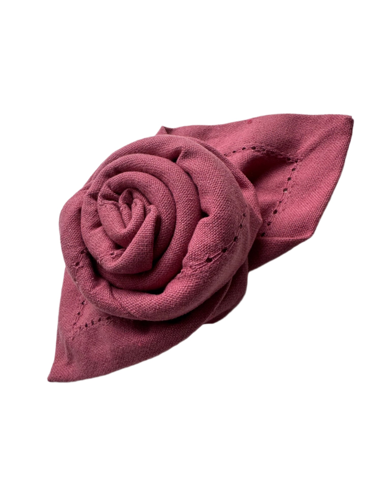 Close-up of a beautifully folded cotton napkin shaped like a rose, showcasing fine stitching and a soft burgundy color with a decorative leaf design
