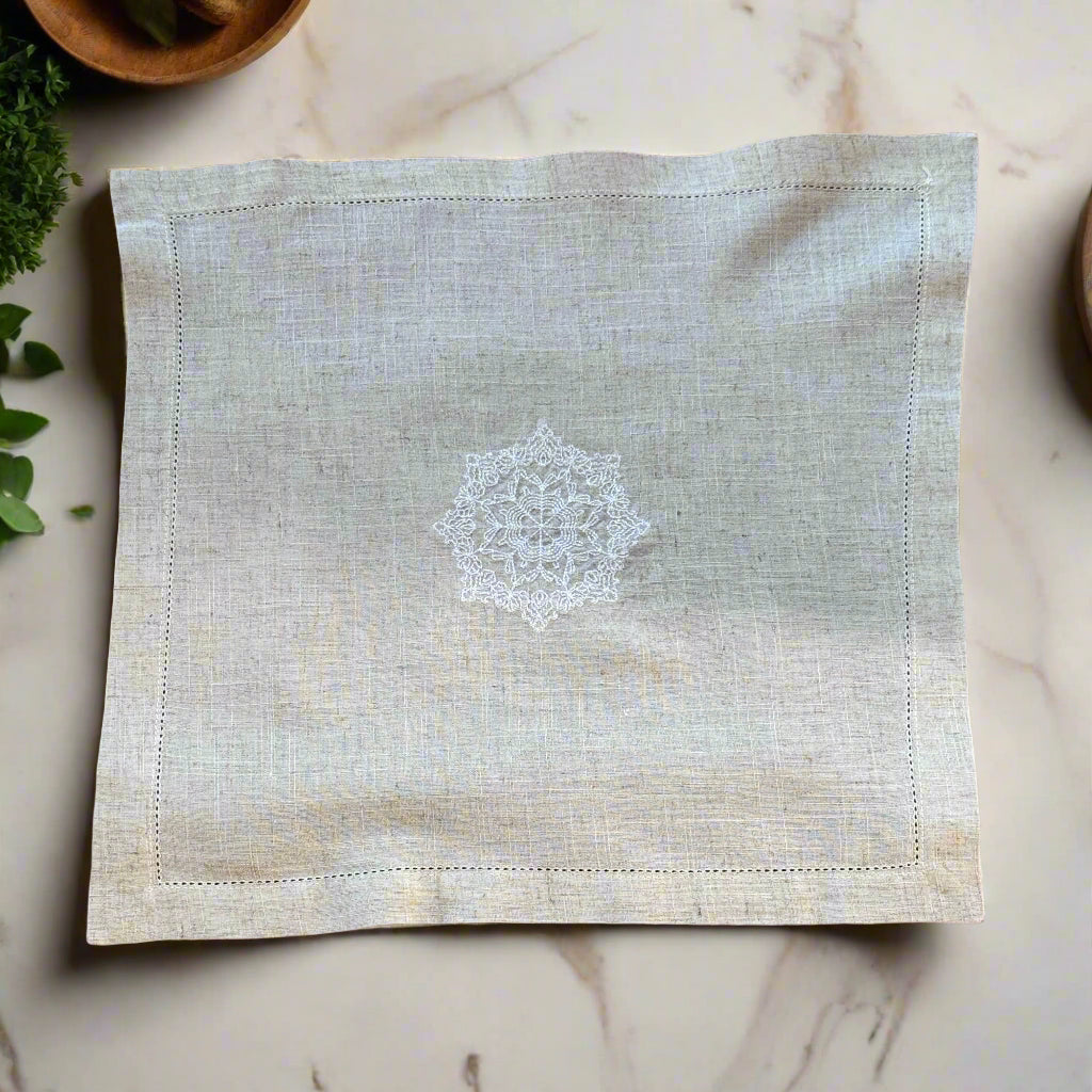 Natural beige linen dinner napkin with delicate embroidered detail and hemstitched edges, 17 x 17 inch reusable cloth napkin styled on an elegant table setting