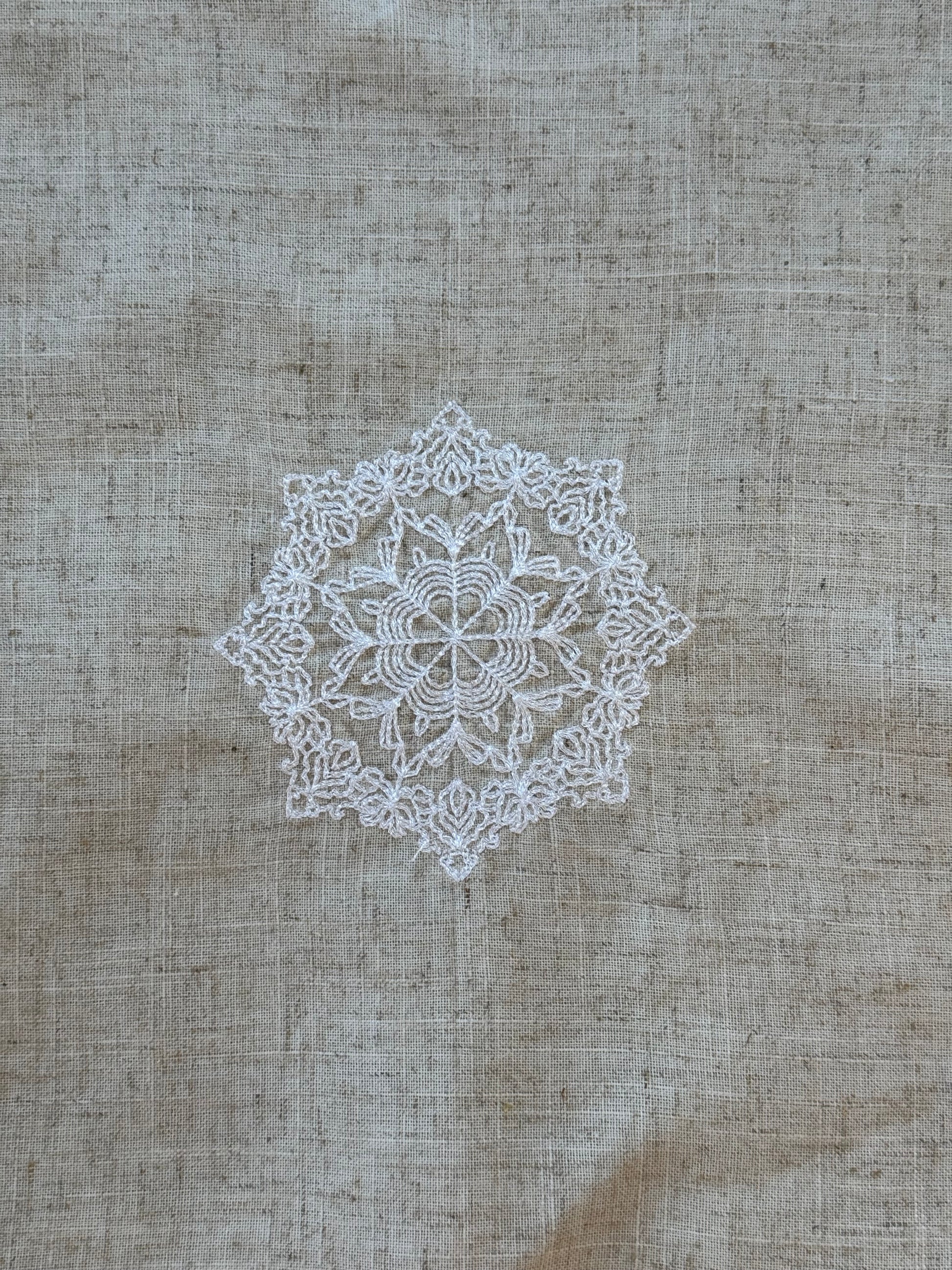 Natural beige linen dinner napkin with delicate embroidered detail and hemstitched edges, 17 x 17 inch reusable cloth napkin styled on an elegant table setting