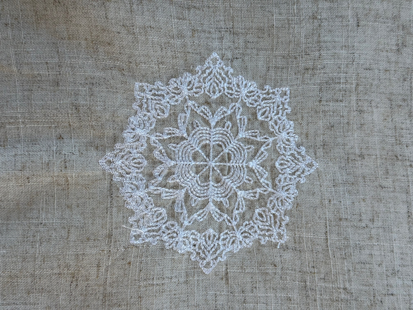 Natural beige linen dinner napkin with delicate embroidered detail and hemstitched edges, 17 x 17 inch reusable cloth napkin styled on an elegant table setting