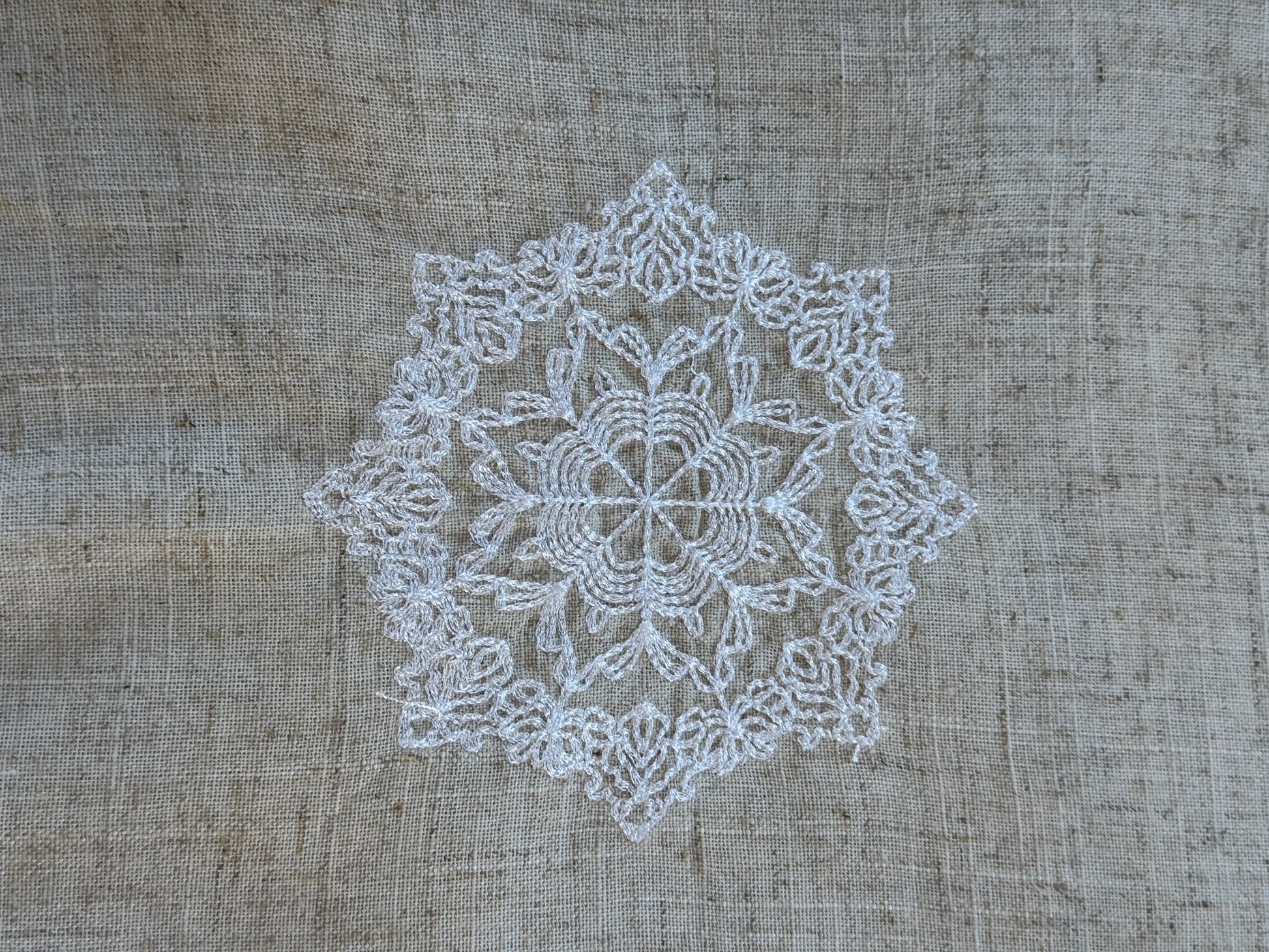 Natural beige linen dinner napkin with delicate embroidered detail and hemstitched edges, 17 x 17 inch reusable cloth napkin styled on an elegant table setting