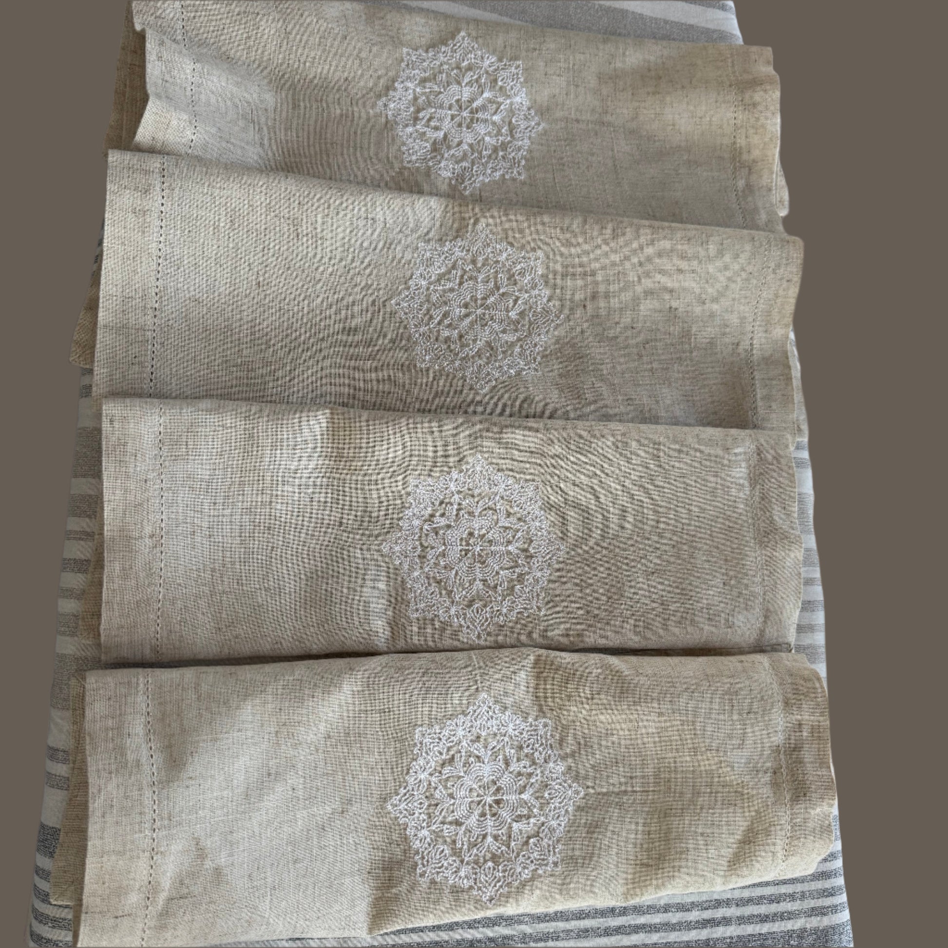 Natural beige linen dinner napkin with delicate embroidered detail and hemstitched edges, 17 x 17 inch reusable cloth napkin styled on an elegant table setting