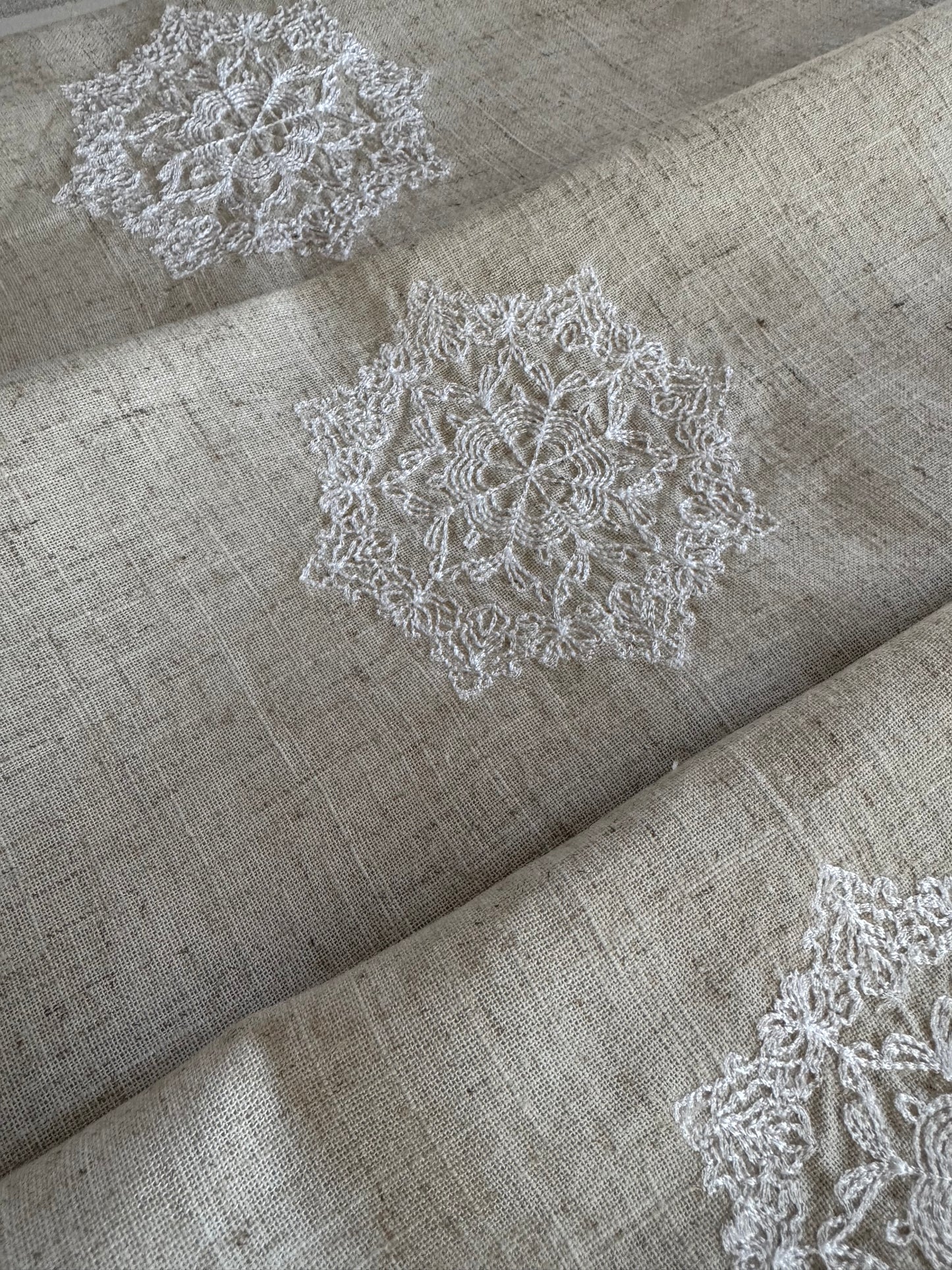 Natural beige linen dinner napkin with delicate embroidered detail and hemstitched edges, 17 x 17 inch reusable cloth napkin styled on an elegant table setting