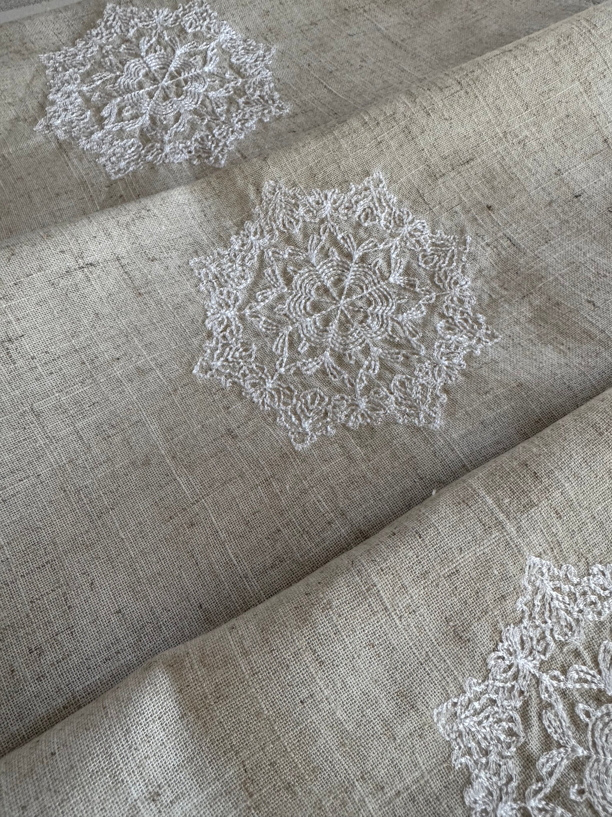 Natural beige linen dinner napkin with delicate embroidered detail and hemstitched edges, 17 x 17 inch reusable cloth napkin styled on an elegant table setting