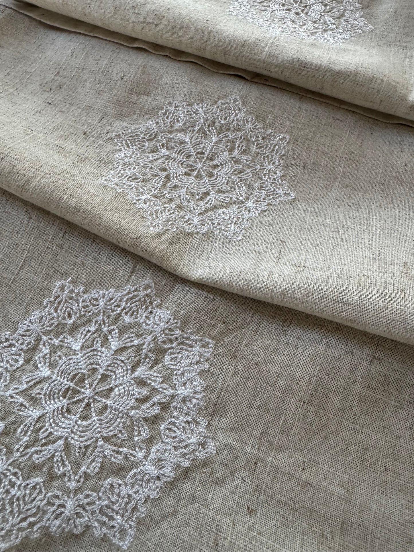 Natural beige linen dinner napkin with delicate embroidered detail and hemstitched edges, 17 x 17 inch reusable cloth napkin styled on an elegant table setting