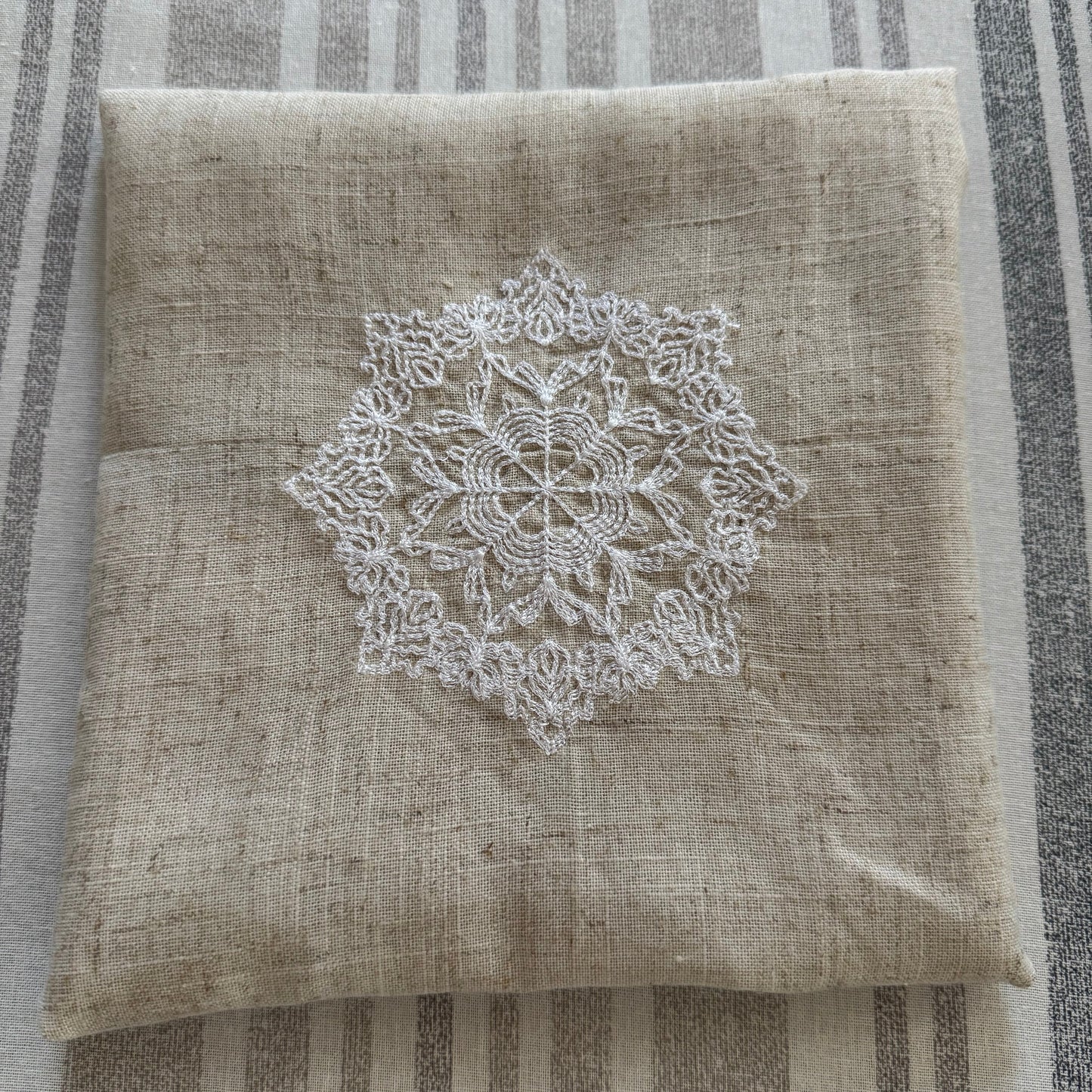 Natural beige linen dinner napkin with delicate embroidered detail and hemstitched edges, 17 x 17 inch reusable cloth napkin styled on an elegant table setting