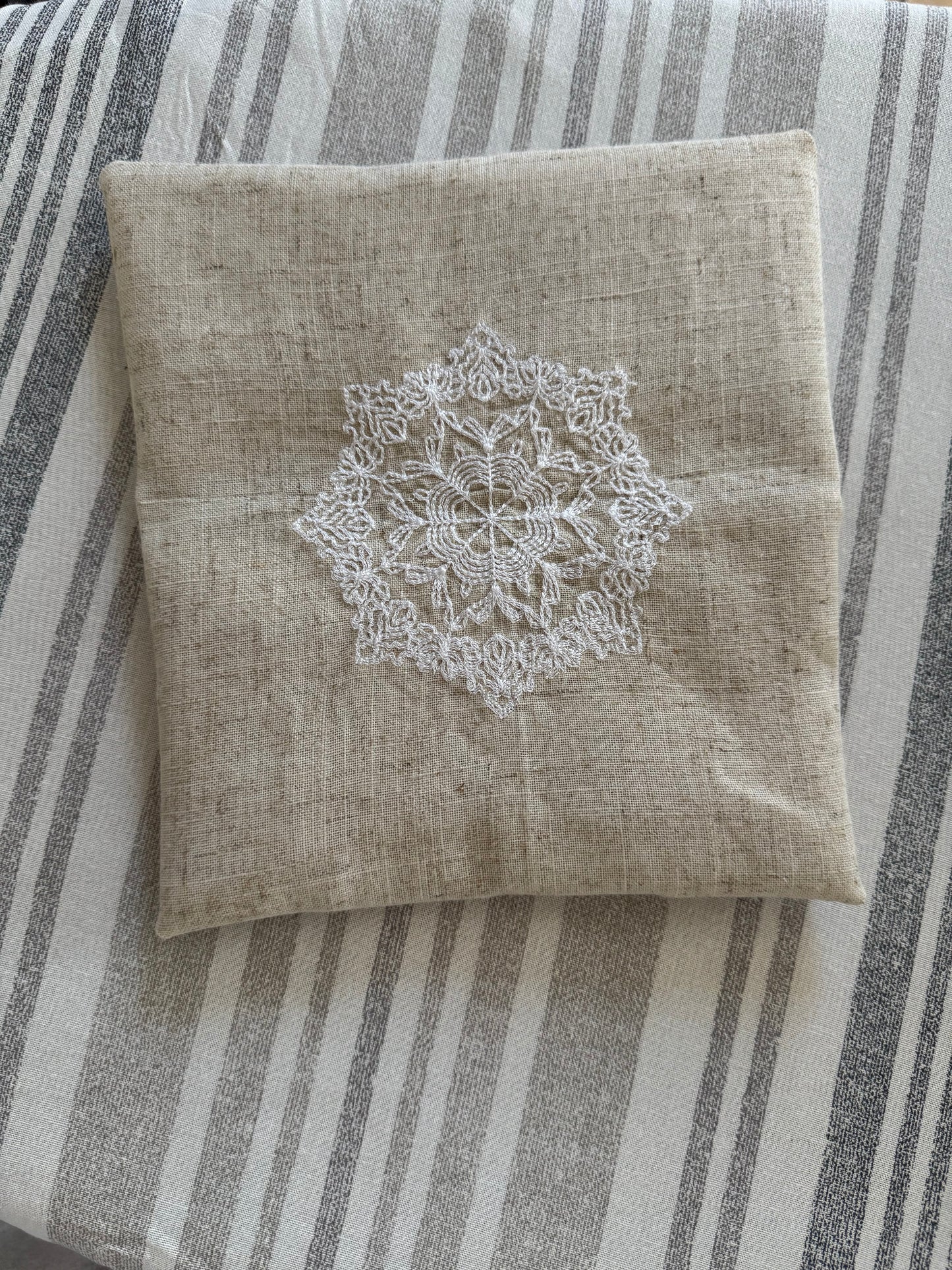 Natural beige linen dinner napkin with delicate embroidered detail and hemstitched edges, 17 x 17 inch reusable cloth napkin styled on an elegant table setting