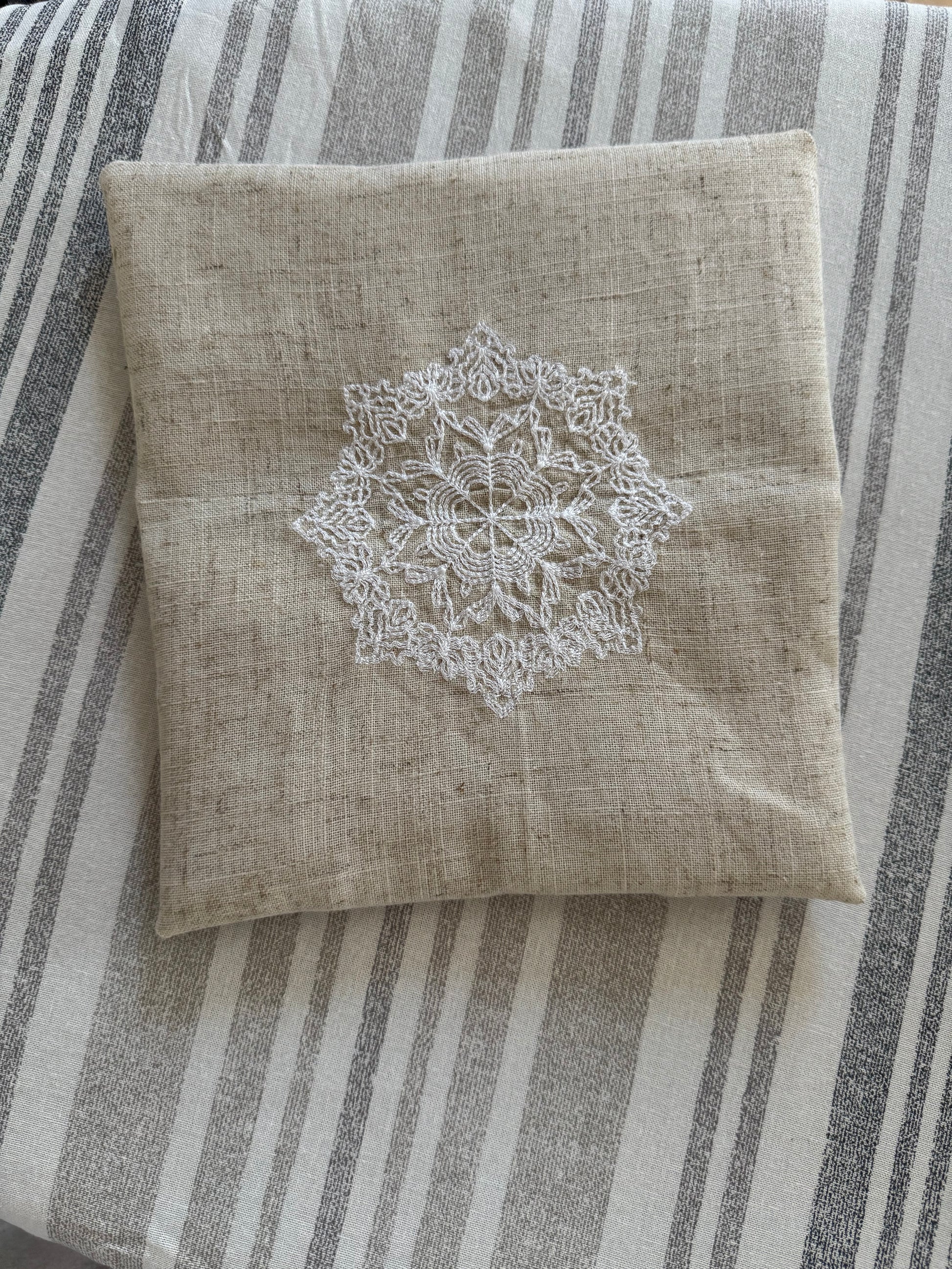 Natural beige linen dinner napkin with delicate embroidered detail and hemstitched edges, 17 x 17 inch reusable cloth napkin styled on an elegant table setting