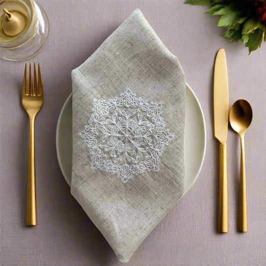Natural beige linen dinner napkin with delicate embroidered detail and hemstitched edges, 17 x 17 inch reusable cloth napkin styled on an elegant table setting
