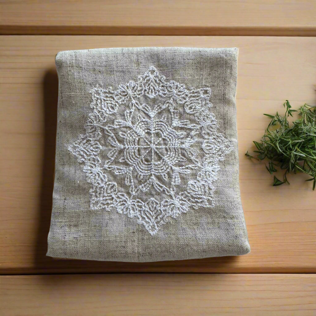 Natural beige linen dinner napkin with delicate embroidered detail and hemstitched edges, 17 x 17 inch reusable cloth napkin styled on an elegant table setting