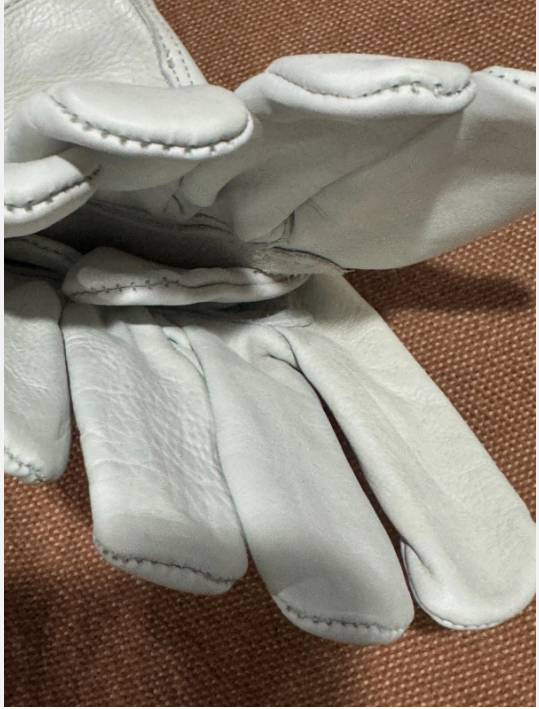 Pair of white leather gloves on a brown textured background