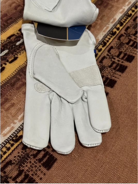 Pair of white leather gloves on a patterned fabric background