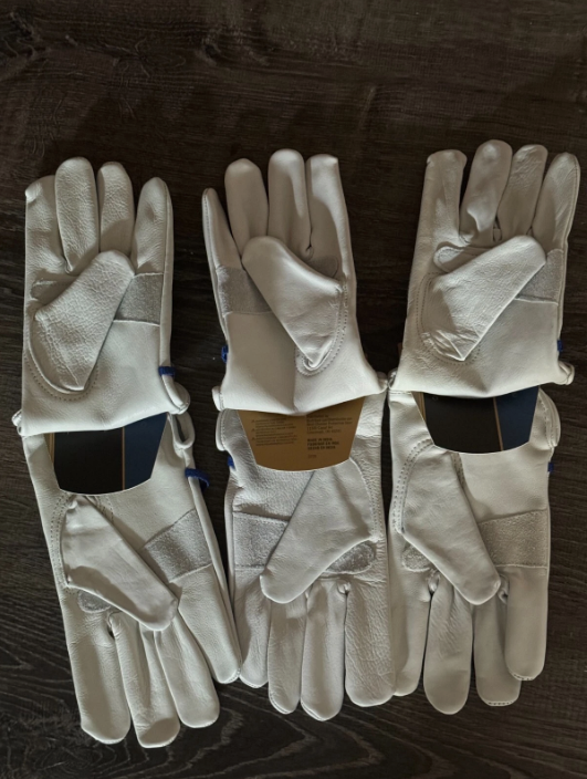 Three pairs of white gloves with black patches on a dark surface
