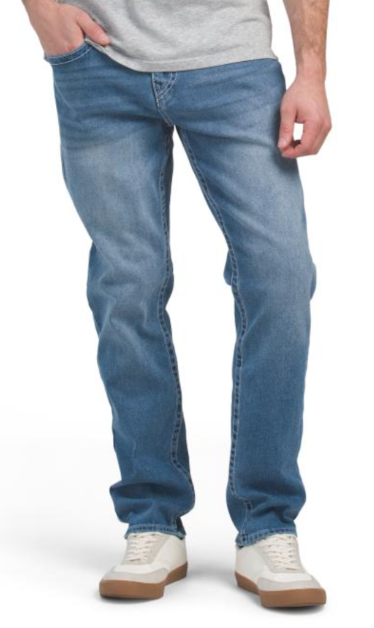 Person wearing blue jeans and white sneakers on a white background