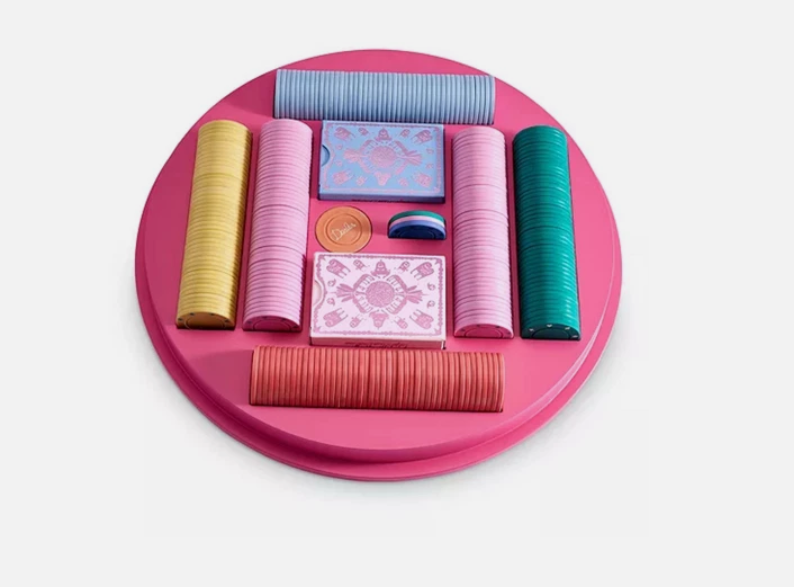 Poker set with colorful chips and cards on a pink tray