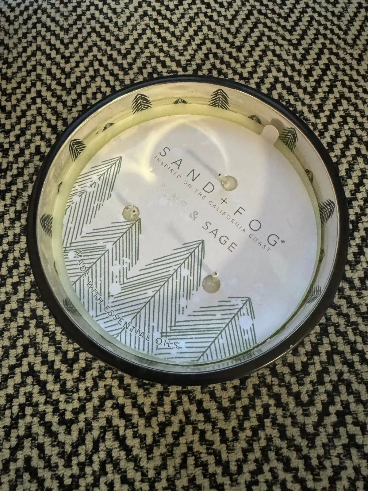 An 18oz Pine and Sage 3-Wick Candle with a Christmas tree motif, hand-poured, displayed in a green glass container surrounded by festive decorations including Christmas trees and wrapped gifts.