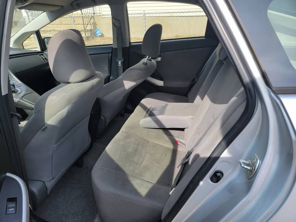 Interior rear seat view of a 2013 Toyota Prius, featuring gray cloth upholstery, center armrest folded down, and a clean, spacious layout with visible front console area.