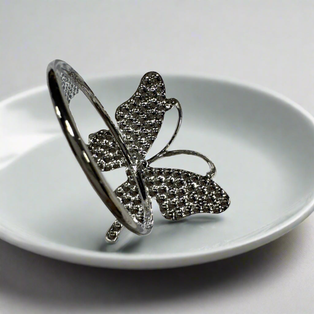 Set of 6 silver butterfly napkin rings displayed on cloth napkin and dish.

