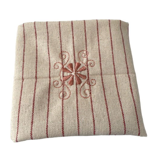 Unbleached cotton cloth napkin with delicate red embroidered floral motif and fine stripe detailing, 12 x 12 inch reusable eco friendly table napkin shown folded on a neutral background
