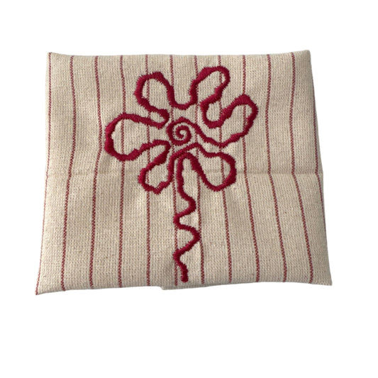 Unbleached cotton cloth napkin with red embroidered floral detail and subtle stripe pattern, 12 x 12 inch reusable eco friendly table napkin displayed folded on a neutral surface
