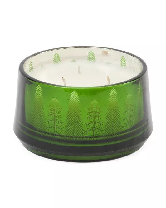 An 18oz Pine and Sage 3-Wick Candle with a Christmas tree motif, hand-poured, displayed in a green glass container surrounded by festive decorations including Christmas trees and wrapped gifts.
