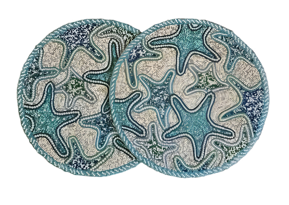 Two handmade beaded placemats with intricate starfish designs in shades of blue, green, and white, featuring high-quality craftsmanship and a coastal-inspired aesthetic
